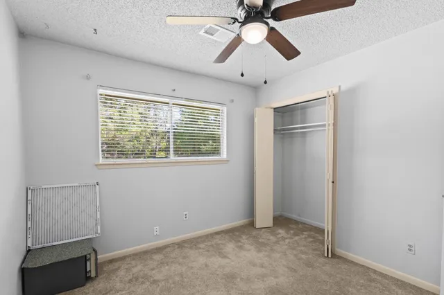 an empty room with windows and fan