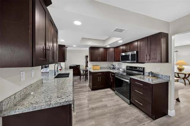 a large kitchen with stainless steel appliances kitchen island granite countertop a stove refrigerator and cabinets