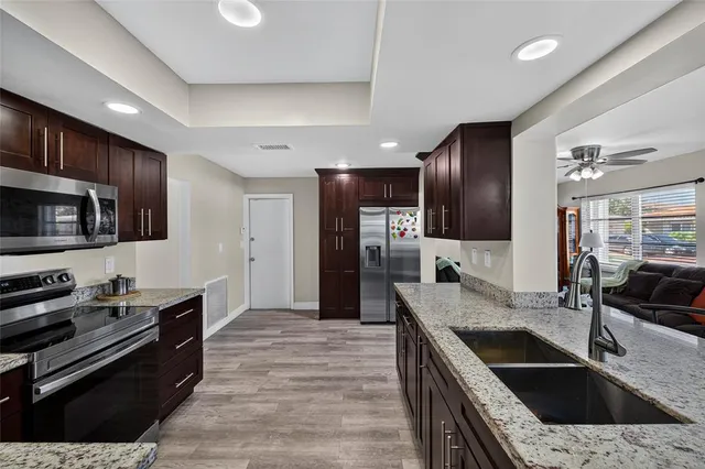 a kitchen with stainless steel appliances granite countertop a sink stove and refrigerator