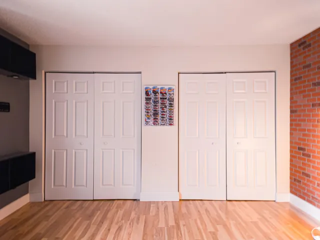 an empty room with wooden floor and closet area