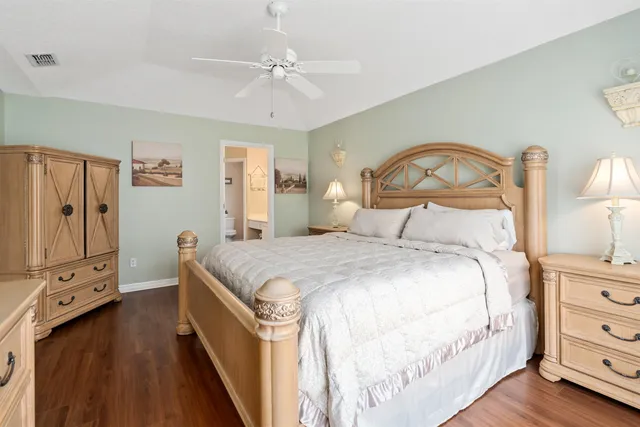a bedroom with a bed a dresser with wooden floor