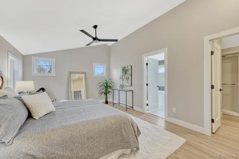 a spacious bedroom with a bed mirror on wall and a chandelier
