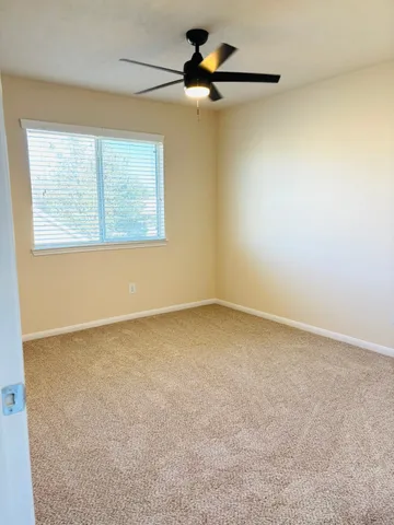 an empty room with a ceiling fan and carpet