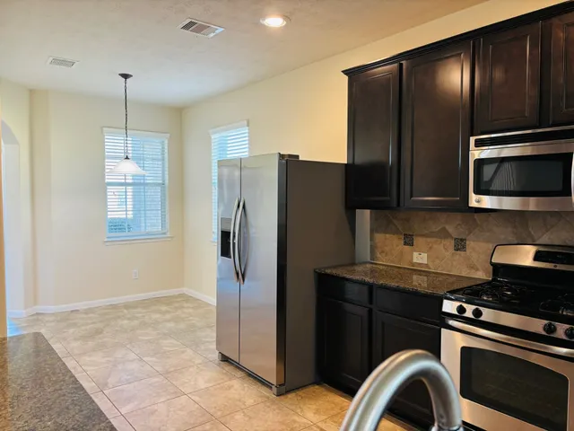 a kitchen with stainless steel appliances granite countertop a refrigerator and a stove top oven
