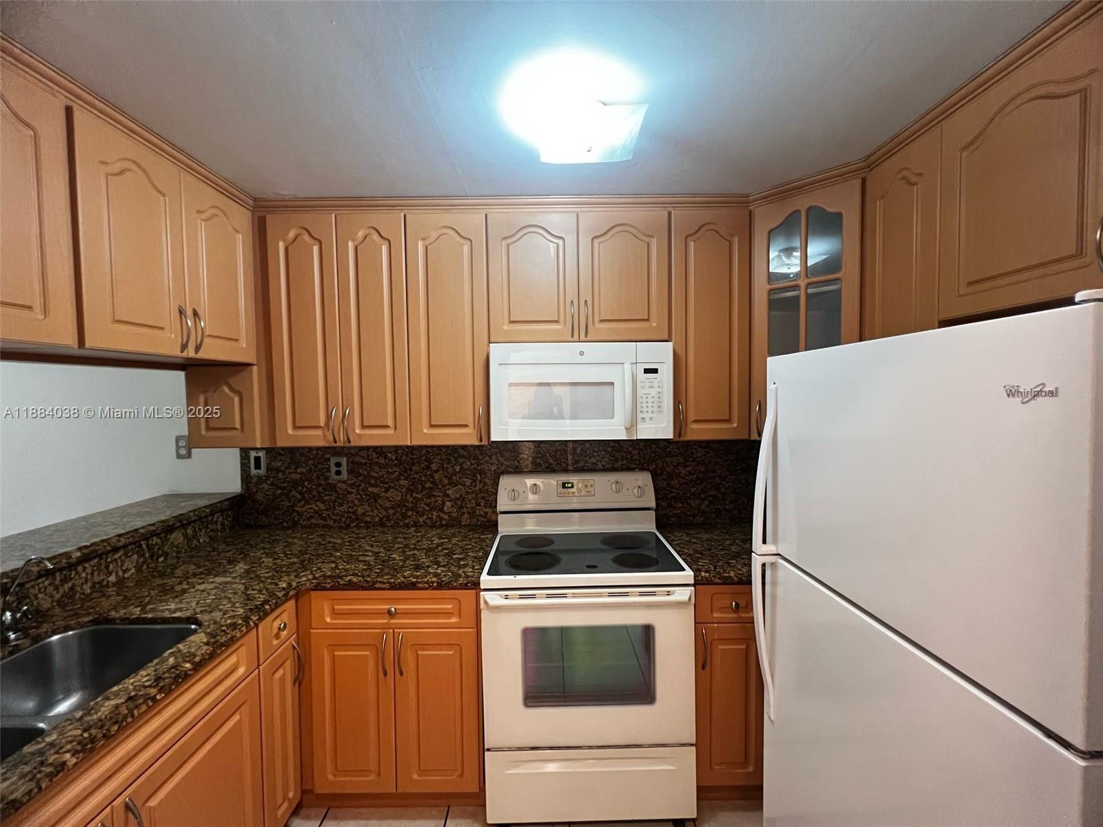 13345 Southwest 59th Lane Miami, FL 33183 - Photo 13 of 29 a kitchen with granite countertop a refrigerator sink and stove