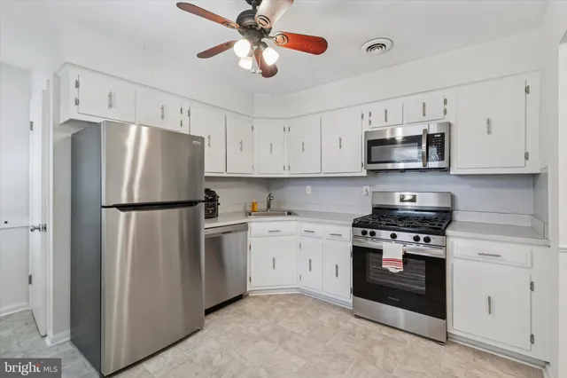 a kitchen with stainless steel appliances granite countertop a refrigerator a stove a microwave oven with white cabinets