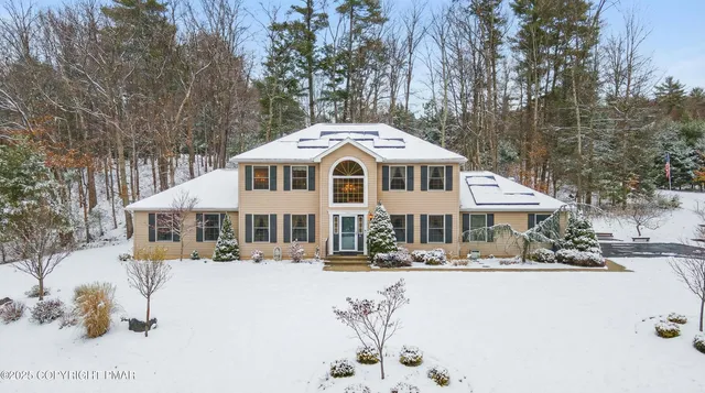 a front view of a house with a yard covered with snow