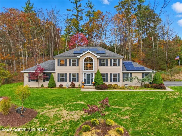 a front view of house with yard and trees in the background