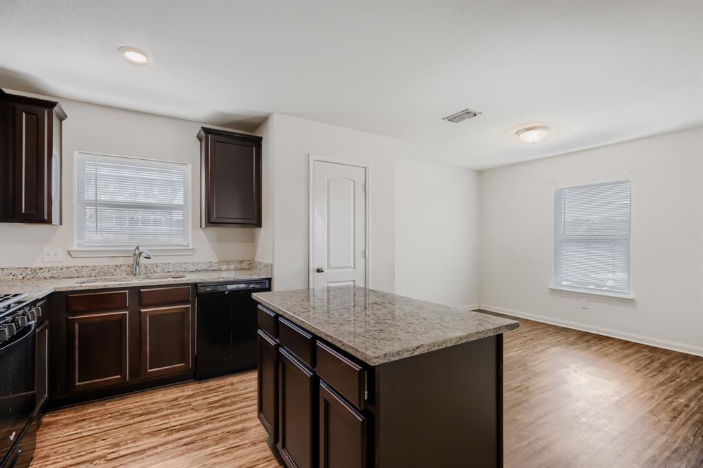 4309 Cat Tail Way Forney, TX 75126 - Photo 11 of 30 Kitchen featuring a central island, dark wood-finish cabinetry, light-colored stone countertops, and wood-finish flooring