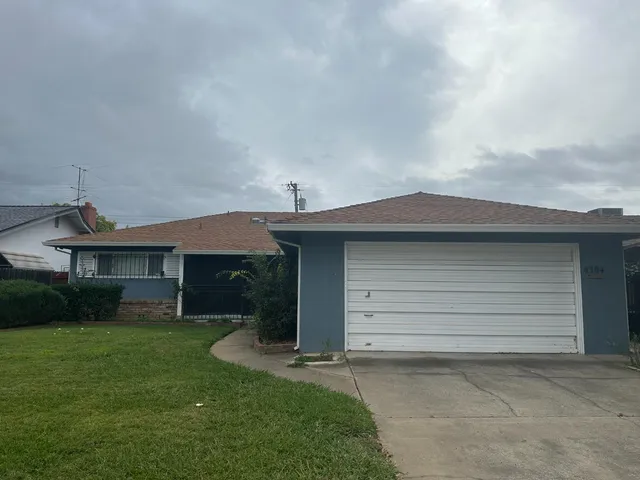 a small white house with a yard and garage