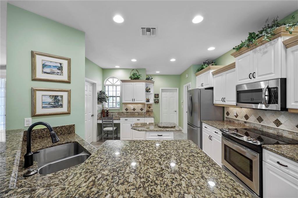 8862 Lely Island Circle Naples, FL 34113 - Photo 11 of 47 a kitchen with stainless steel appliances granite countertop a stove top oven a sink dishwasher a refrigerator and a dining table with wooden floor