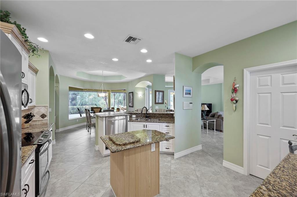 8862 Lely Island Circle Naples, FL 34113 - Photo 12 of 47 a kitchen with stainless steel appliances kitchen island granite countertop a refrigerator and cabinets