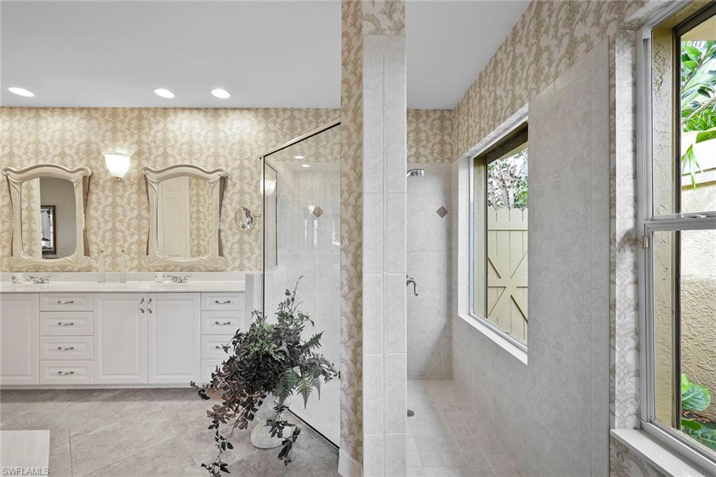 8862 Lely Island Circle Naples, FL 34113 - Photo 17 of 47 a bathroom with a granite countertop sink a mirror and a shower