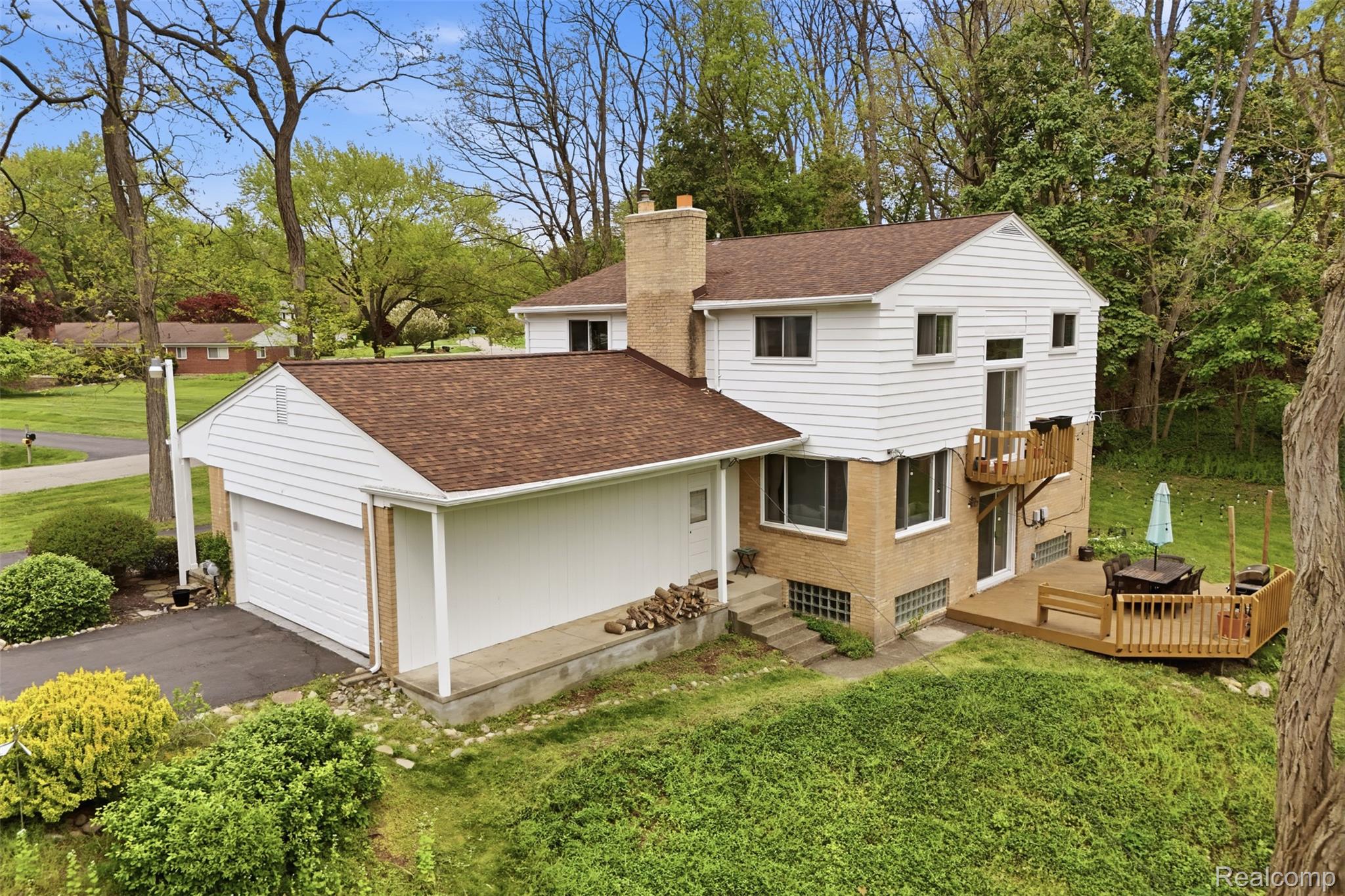 47129 Dunsany Road Northville, MI 48167 - Photo 47 of 49 Rear view of house with roof with shingles, a chimney, a lawn, a wooden deck, and driveway