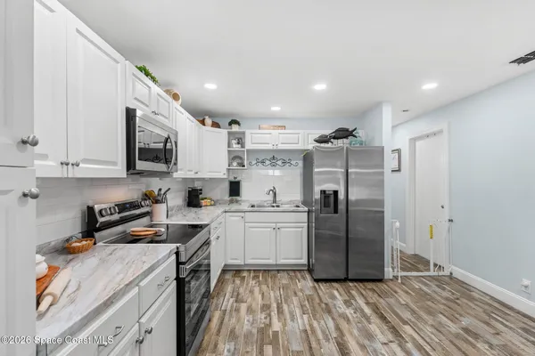 a kitchen with stainless steel appliances granite countertop a refrigerator sink and white cabinets
