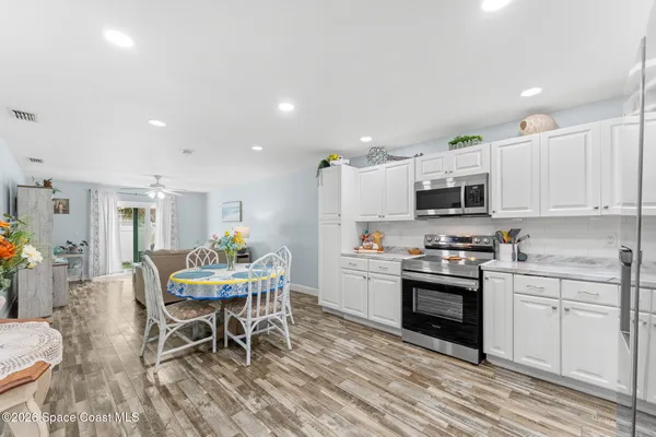 a kitchen with stainless steel appliances a dining table chairs stove refrigerator and cabinets