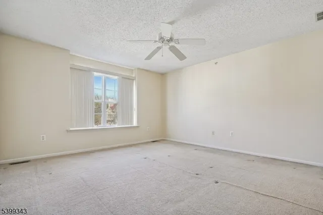 an empty room with a window and a ceiling fan