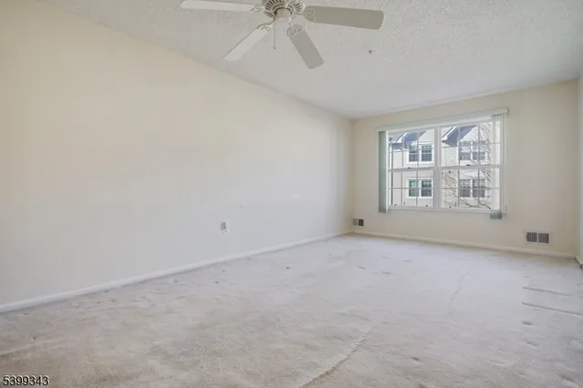 an empty room with windows and ceiling fan