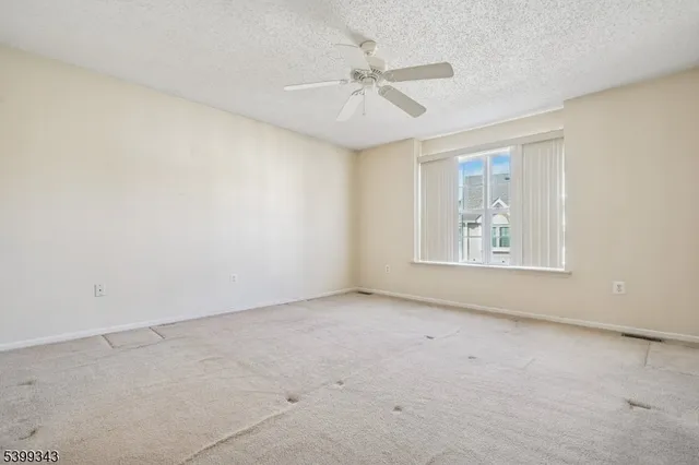 an empty room with windows and fan