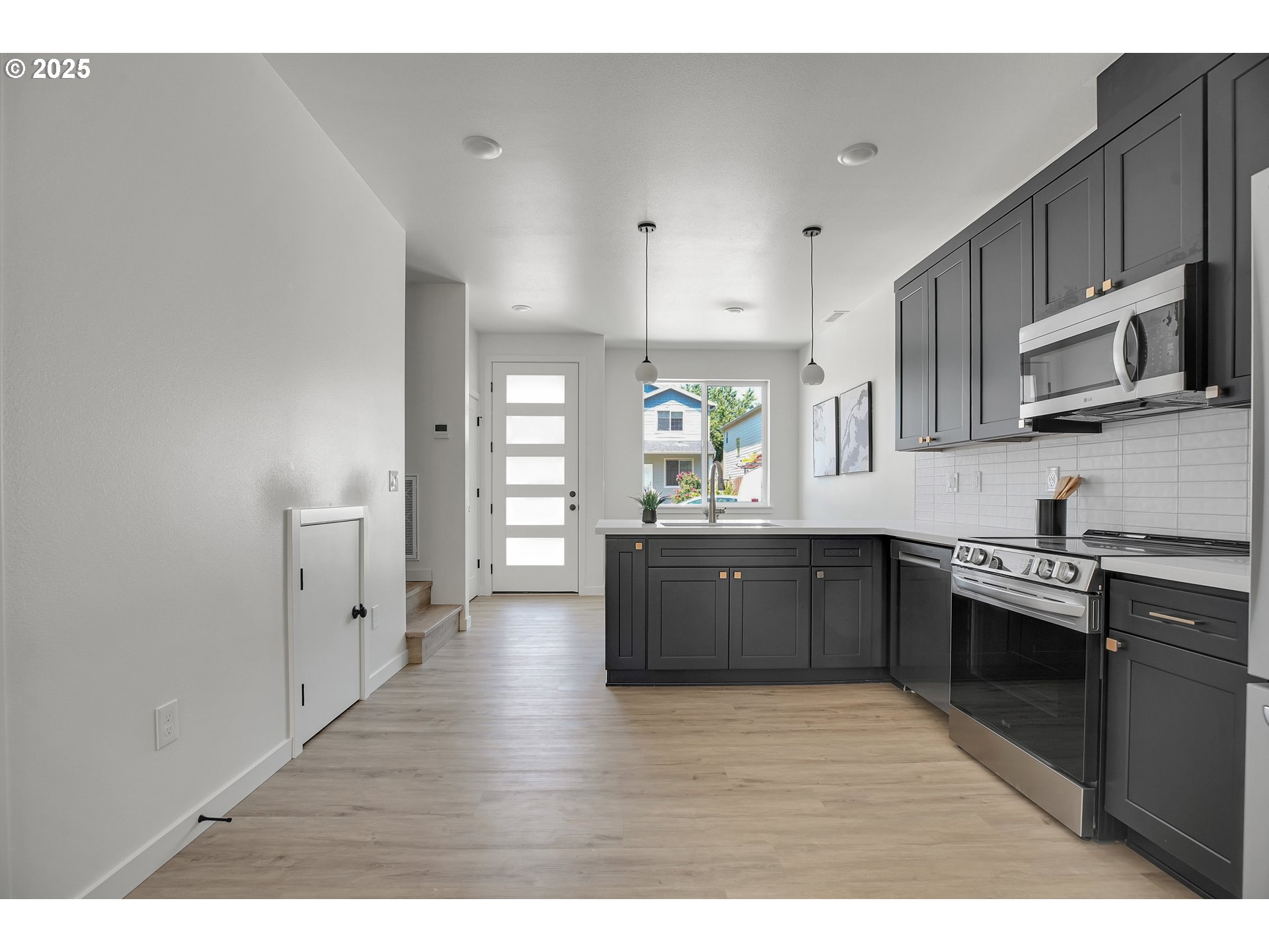 14870 Northeast Couch Street, Unit 12 Portland, OR 97230 - Photo 35 of 42 a kitchen with stainless steel appliances kitchen island granite countertop a stove a sink and a microwave