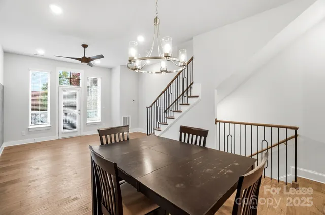 a dining area with a table chairs wooden floor and view kitchen