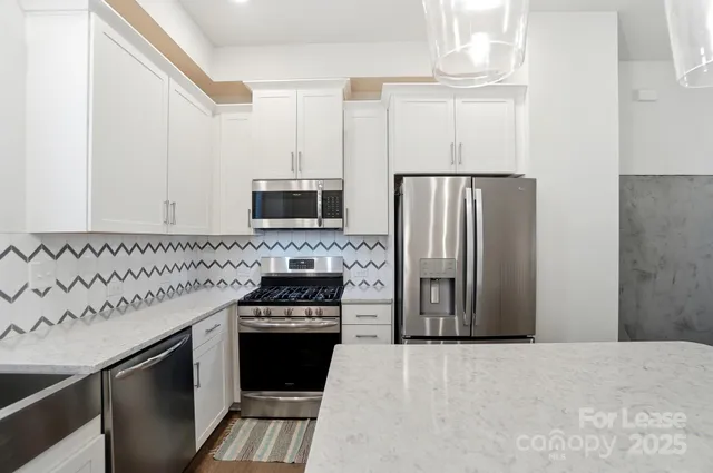 a kitchen with stainless steel appliances a stove a sink and white cabinets