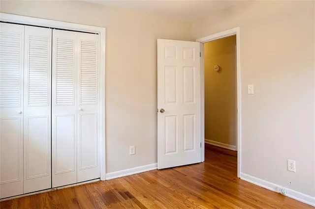 a view of an empty room with wooden floor and closet
