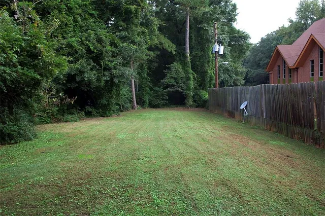 a view of a backyard with a trees and wooden fence