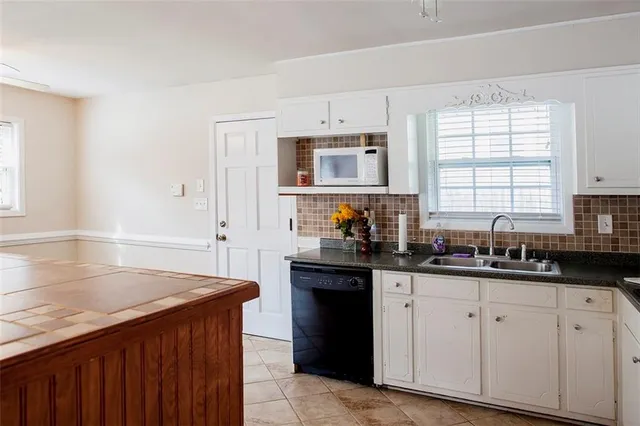 a kitchen with granite countertop a sink dishwasher stove and cabinets
