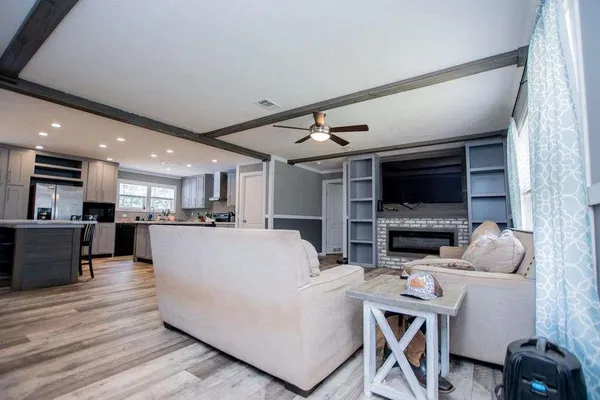 a living room with furniture a flat screen tv and kitchen view