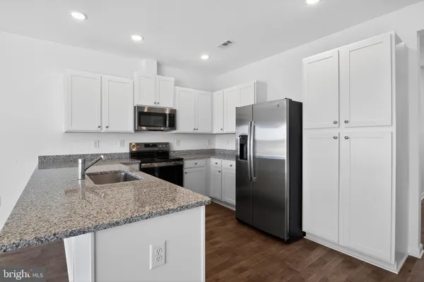 a kitchen with granite countertop a refrigerator and a sink