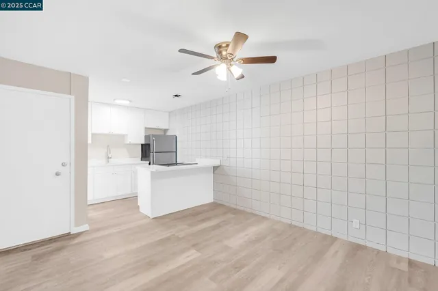 a view of a kitchen with kitchen island a sink wooden floor and a refrigerator