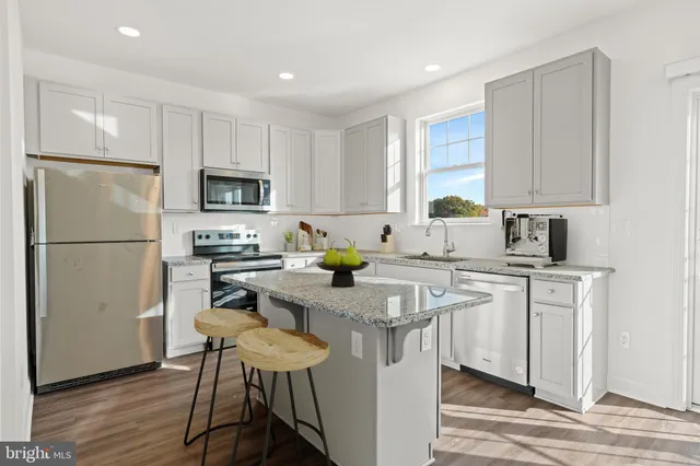 a kitchen with stainless steel appliances a refrigerator a sink a stove a table and chairs