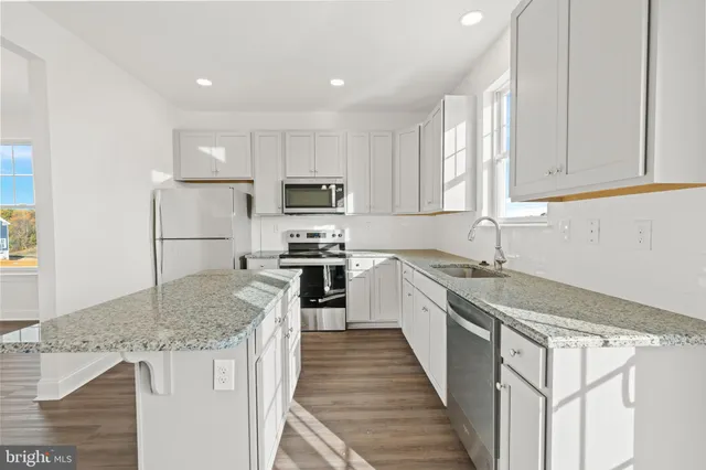 a kitchen with kitchen island granite countertop a sink stove and refrigerator