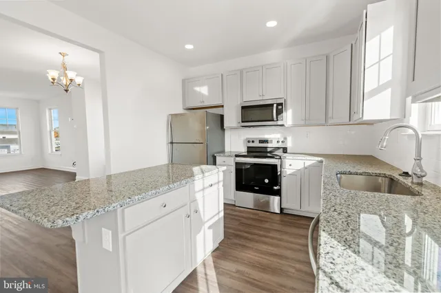a kitchen with granite countertop a refrigerator stove and sink