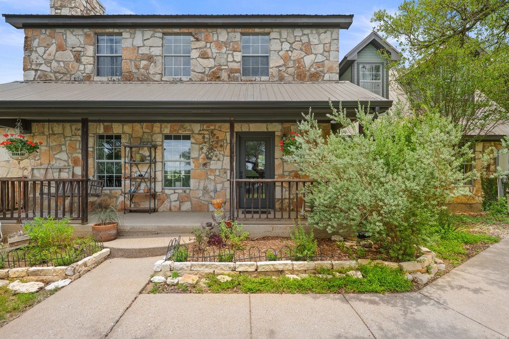 290 Sunset Ridge Dripping Springs, TX 78620 - Photo 4 of 36 A welcoming stone facade with a covered porch and lush landscaping invites you home.