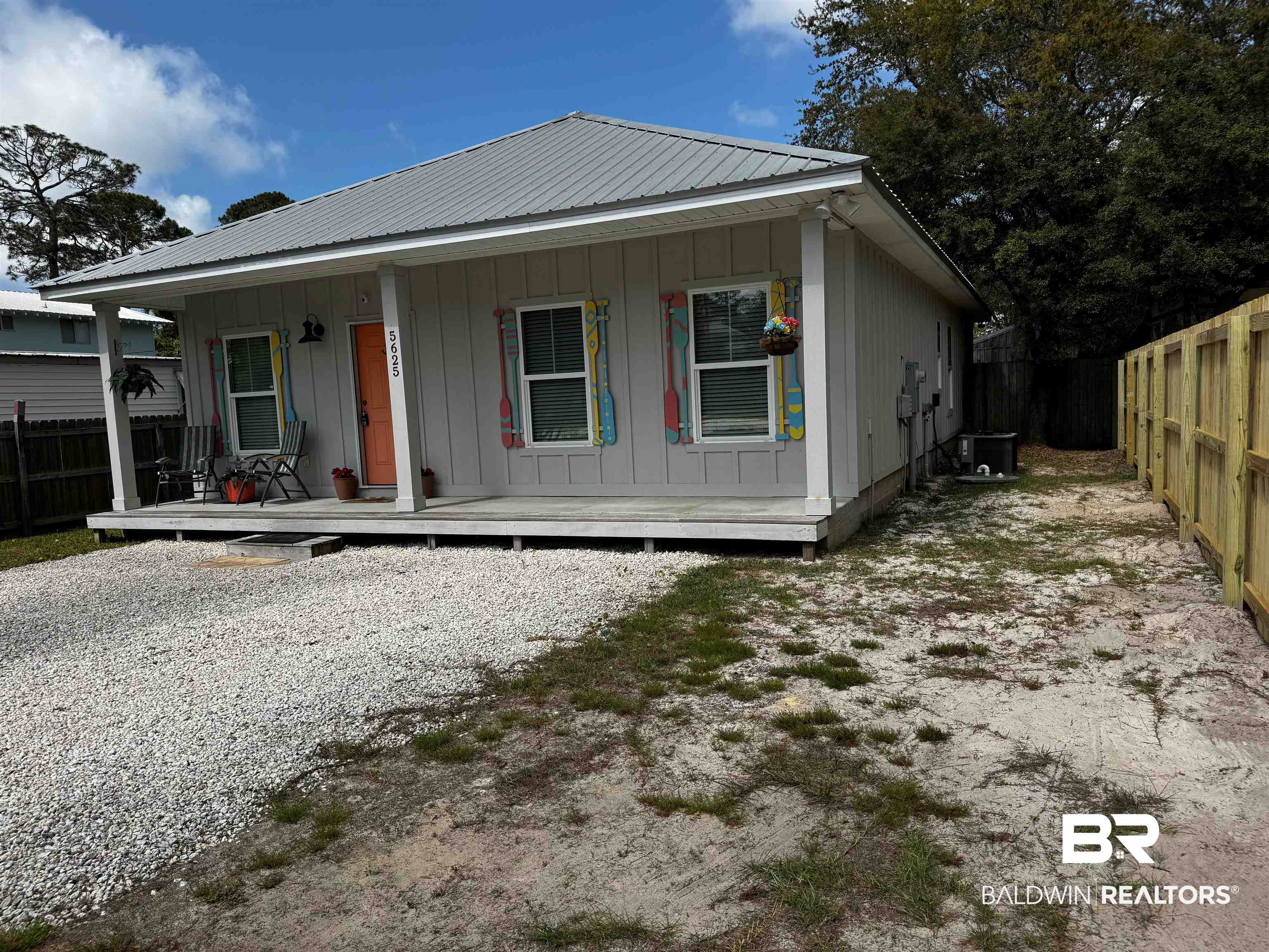 5625 Georgia Street Orange Beach, AL 36561 - Photo 4 of 30 View of front of house featuring board and batten siding, a fenced backyard, central air condition unit, covered porch, and metal roof