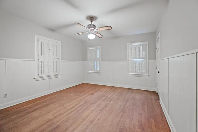 a view of empty room with wooden floor and fan