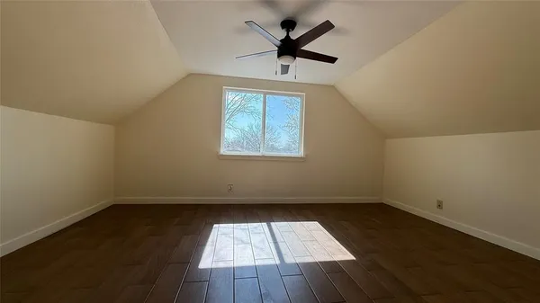 an empty room with wooden floor ceiling fan and windows