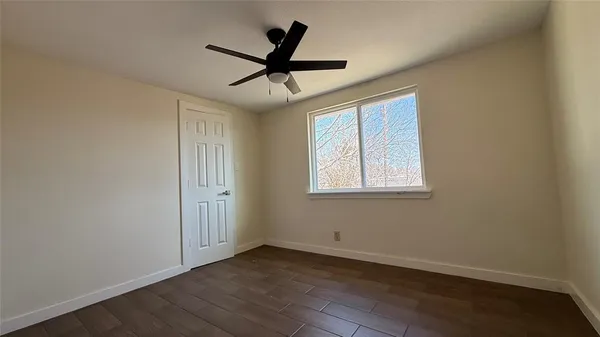 an empty room with a window and a ceiling fan