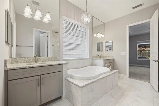 a bathroom with a granite countertop sink a large mirror and a bathtub