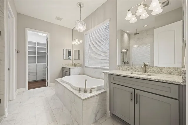 a spacious bathroom with a granite countertop sink a mirror and a bathtub