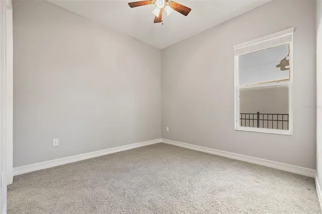 an empty room with a fan & a window