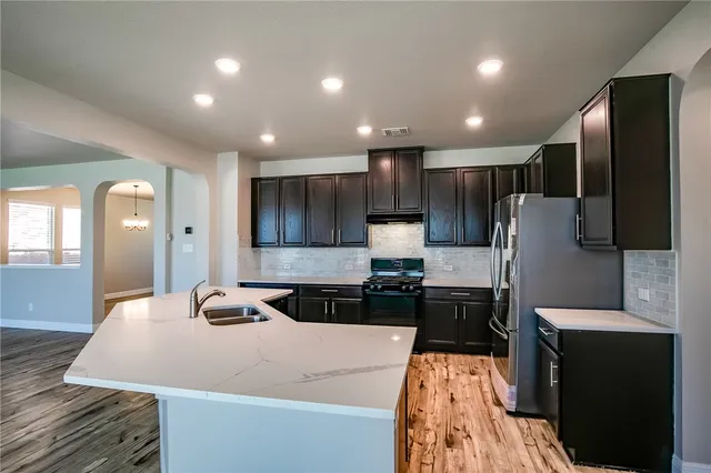 a kitchen with kitchen island a counter top space a sink and a stove