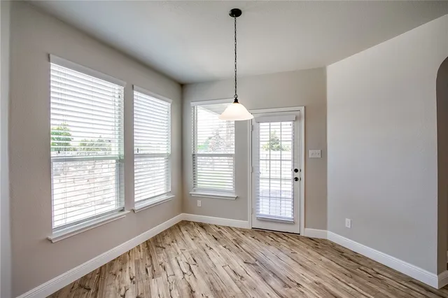 a view of an empty room with a window and wooden floor