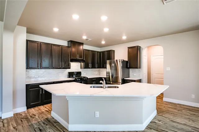 a view of a kitchen with kitchen island a sink and wooden floor