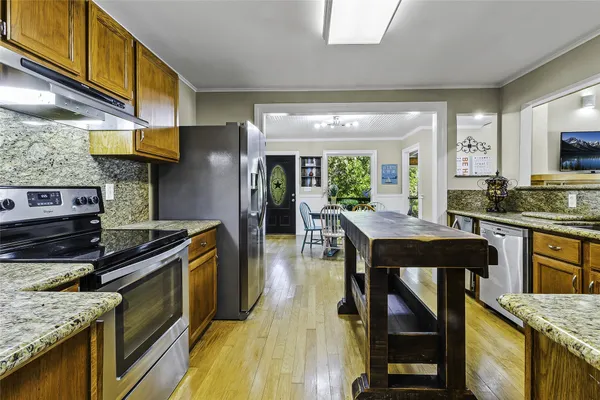 a kitchen with stainless steel appliances granite countertop a stove refrigerator and cabinets