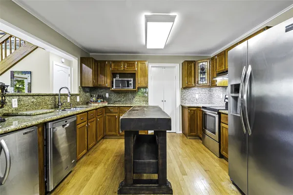 a kitchen with stainless steel appliances granite countertop a sink a stove and cabinets