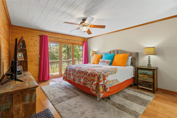 a bedroom with a bed a flat screen tv and a large window