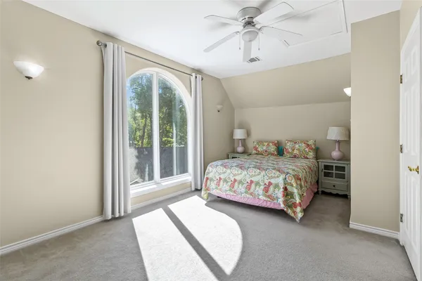 a bedroom with a bed lamp and a large window